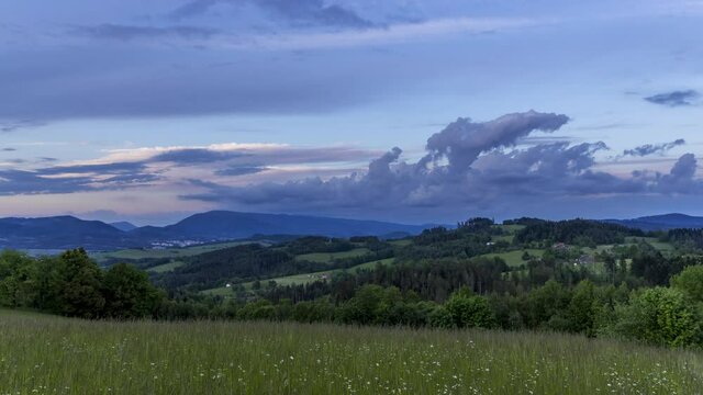 Timelapse of clouds moving through the landscape over the city lying between the valley during sunset view from the grass field on the dark clouds Beskydy region Roznov pod Radhostem