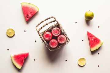 Tasty summer bottled watermelon drink in a basket and slices of fresh fruits on white background