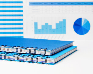 Notebooks in blue and blue with a spring on the table against the background of financial charts. Investment concept or business idea. Accounting and finance.