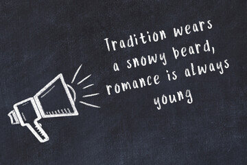 Chalk sketch of loudspeaker on black desk and movitational quote