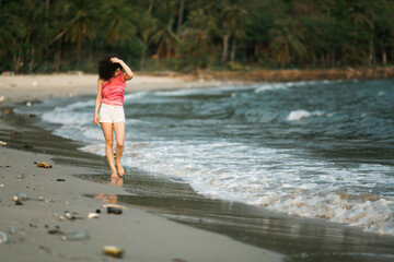 Woman walks along a polluted tropical beach. Environmental problems.