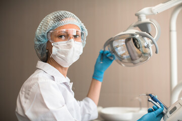 Portrait of female dentist doctor holding a lamp in the dental clinic.
