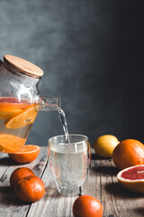 Citrus tea in a transparent teapot on a table with grapefruit and on a wooden table. Healthy drink.