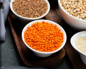 Red lentils and buckwheat in a white bowl on a wooden board