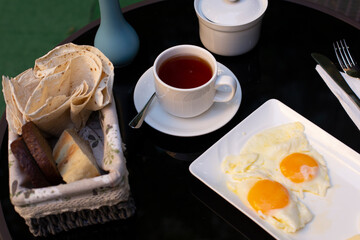 Two fried eggs, a cup of tea and bread