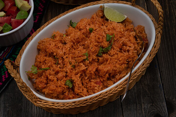 Mexican rice served in ceramic dish on wooden table