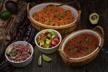 Vegan mexican rice, vegan chili, pickled onion and avocado tomato salad on wooden table