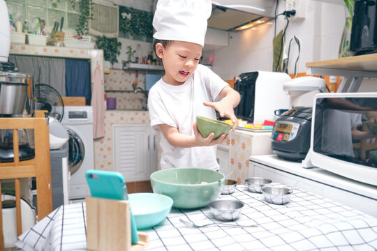 Cute happy smiling Asian little kindergarten boy having fun cooking breakfast and recording a video for his followers, Young blogger make vlog for social media channel, photo in real life interior