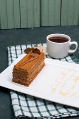 A slice of medovik cake with a cup of tea