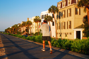 Fototapeta na wymiar A Jogger Passes the Stately Antebellum Homes Along Charleston Waterfront
