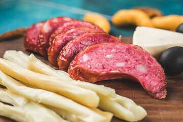 Sausage with cheese sticks and crackers on a wooden board