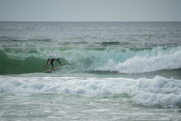 Young male surfer catching a wave and doing a big turn on it at Manly beach in Australia, craving,...