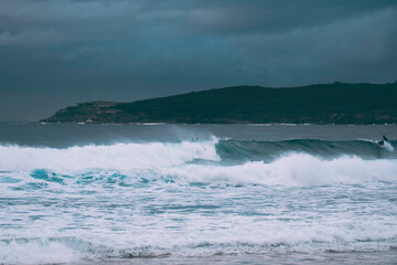 one big wave breaking at the beach on a stormy day