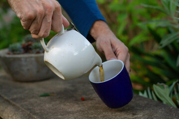 man pouring a cup of tea in the backyard
