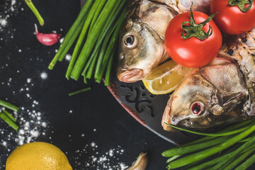 Fototapeta na wymiar Fish heads with herbs, lemon and tomatoes with sea salt around