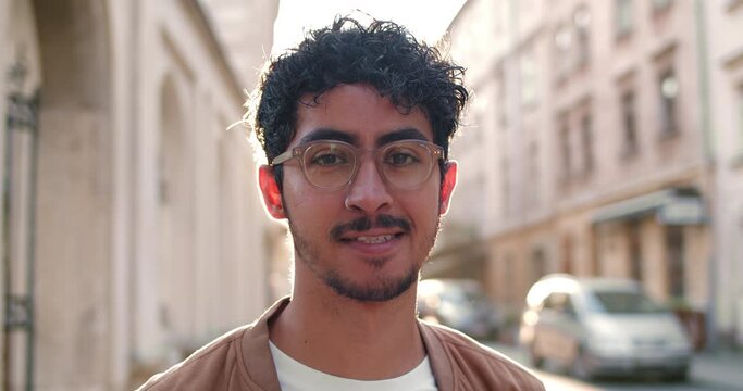 Close up view of young man in glasses looking to camera and smiling. Portrait of handsome guy with nose ring standing at old city street.Concept of people and real life