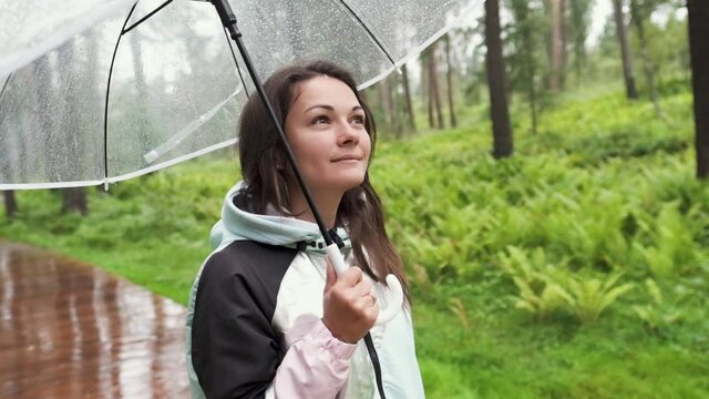 a young woman walks through the woods in the rain with an umbrella. attractive brunette walks in the park in the rain