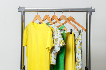 Bright yellow, green summer clothes hanging on the rail. Clothing for the holiday, relaxation at sea, summer walks.