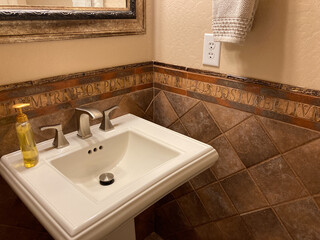 Pedestial sink in bathroom with tiled walls and gold fleck mirror