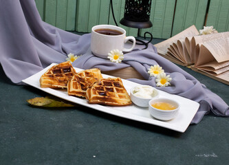 Waffles sliced and served with caramel sauce and a cup of tea