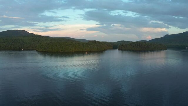 Drone shot going up and down on a beautiful lake and forest at colorful dusk in the Eastern Township