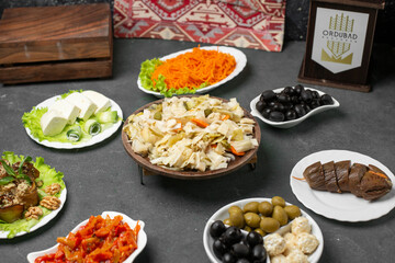 Marinated cabbage salad served with cheese and olives on blue table