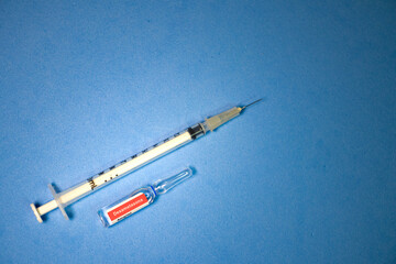 Ampola de dexametasona, em portugu&ecirc;s, com seringa em fundo azul.