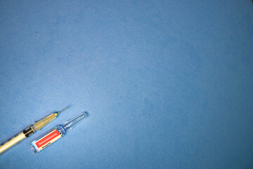 Ampola de dexametasona, em português, com seringa em fundo azul.