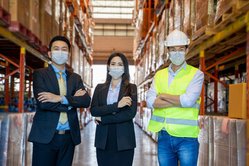 Business people with warehouse workers wearing hard hats standing in aisle between tall racks with packaged goods,Warehouse workers in warehouse with managers.