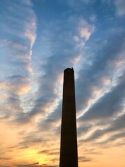 Tall chimney smokestack against sunrise