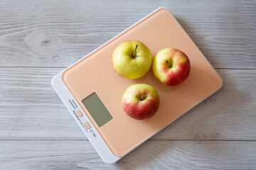 fresh apples on kitchen scales on a natural gray background