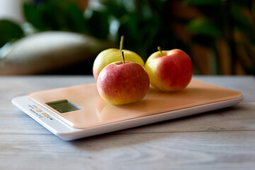 fresh apples on kitchen scales on a natural gray background