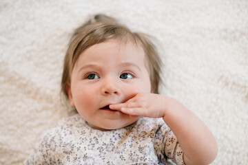 Closeup of a baby thinking with hand in mouth