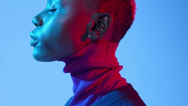 Close-up profile shot of a beautiful African American woman artistically lit under colored studio lights.