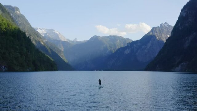Aerial view Panning shot, man paddle boarding SUP on the lake, Scenic view of the Rocky mountain side.