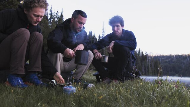 Low shot of group of backpackers in nature sharing coffee and plan hike on map