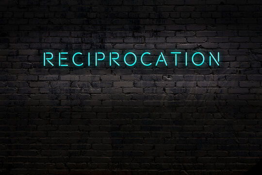 Neon sign. Word reciprocation against brick wall. Night view
