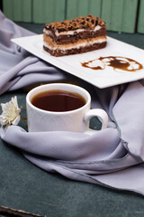 A slice of medovik cake with a cup of tea on blue table