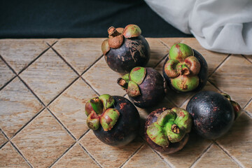 Delicious fresh mangosteen and cross section showing the thick purple skin and white flesh of the queen of tropical fruit in a supermarket local market.