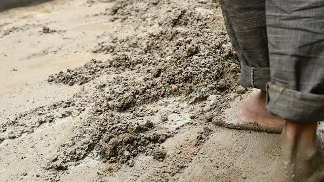 Indian labour mixing cement and water manually on floor using a shovel. Stock footage.