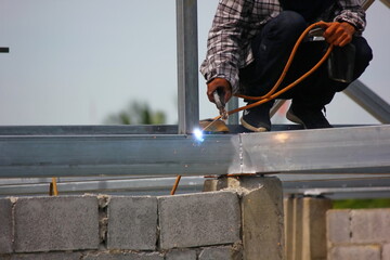the worker welding metal on roof structure