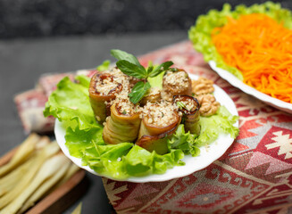 Fried eggplant roll salad in white plate on a carpet