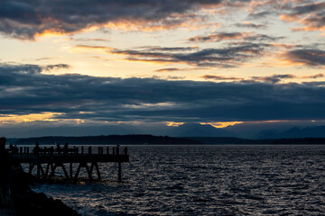 View towards the Olympic Mountains across from Alki Beach in West Seattle on a late summer day. There are dramatic clouds over the Sound.