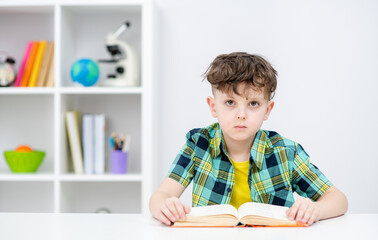 Portrait of a smart boy with an open book at school