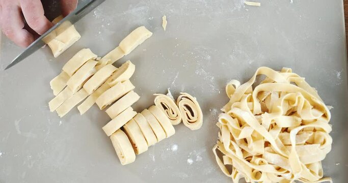 Making homemade pasta. Chef cuts dough by pieces, making macaroni from them.