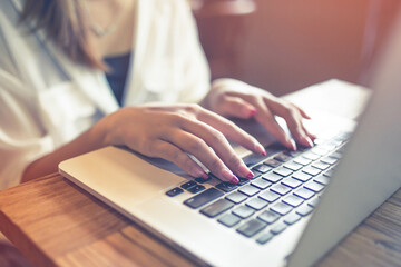 Closeup of a woman hands typing a laptop on the table .business concept