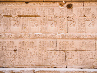 Ancient brickwall with inscriptions and paintings, close up view. Ruins of Karnak temple. Photographed in Luxor, Egypt. Selective soft focus. Blurred background