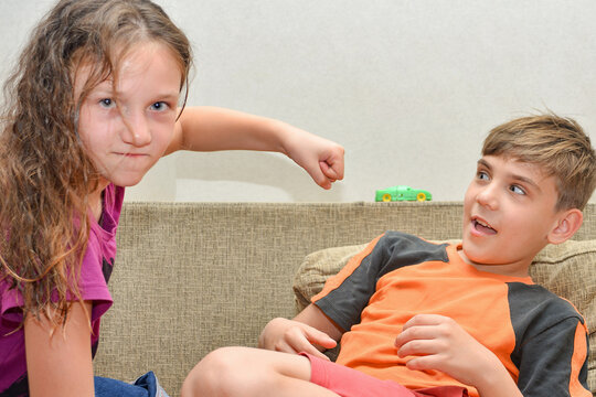 The Wicked And Cruel Older Sister Swings Her Fist At Her Younger Brother To Beat Him. Cruelty And Domestic Violence, Social Problems Without Proper Education.