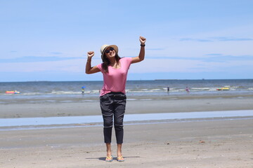 Asian women wearing pink shirts are stand with joy and freshness. On beach on summer holiday, Summer concept. Happy summer