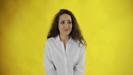 Guilty young beautiful woman in shirt standing in hesitation on yellow background